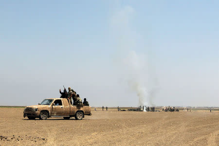 Fighters of the Syrian Islamist rebel group Jabhat Fateh al-Sham cheer on a pick up truck near the wreckage of a Russian helicopter that had been shot down in the north of Syria's rebel-held Idlib province, Syria August 1, 2016. REUTERS/Ammar Abdullah