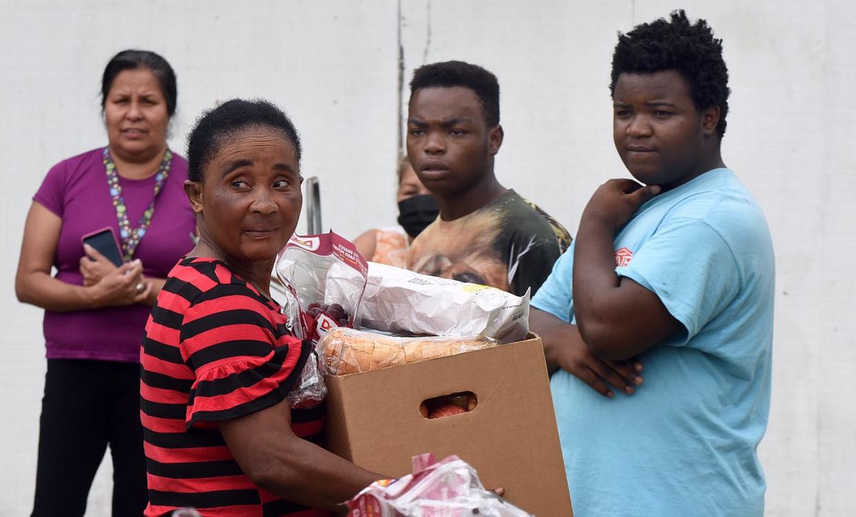 <span class="caption">People affected by the downturn in the economy caused by coronavirus at a food bank in Central Florida in April, 2020. </span> <span class="attribution"><a class="link " href="https://www.gettyimages.com/detail/news-photo/people-wait-in-line-as-a-woman-carries-a-box-of-food-news-photo/1209343205?adppopup=true" rel="nofollow noopener" target="_blank" data-ylk="slk:Paul Hennessy/NurPhoto/Getty Images;elm:context_link;itc:0;sec:content-canvas">Paul Hennessy/NurPhoto/Getty Images</a></span>