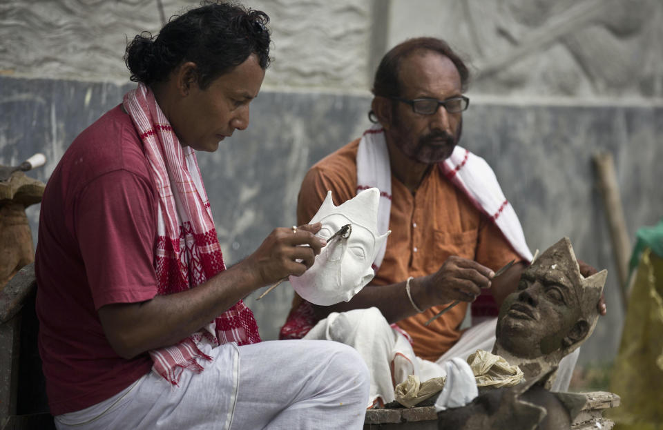 In this Tuesday, Aug. 7, 2018, photo, traditional mask makers Khagen Goswami, left, and Hemachandra Goswami work on masks at Samaguri Satra, a Vaishnavite monastery, in Majuli, India. Vaishnavite practice is credited with preserving the culture of mask-making, an integral part of the dance dramas or Bhaonas. At the Samaguri Satra, the monks use locally available bamboo, cane, clay, paper, jute and cow dung to shape and paint masks depicting characters from Hindu mythology. (AP Photo/Anupam Nath)