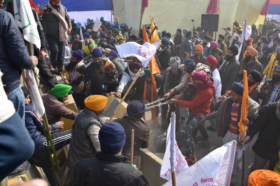 Protesting farmers remove barricades as they march to the capital during India's Republic Day celebrations in New Delhi, India, Tuesday, Jan. 26, 2021. Tens of thousands of farmers drove a convoy of tractors into the Indian capital as the nation celebrated Republic Day on Tuesday in the backdrop of agricultural protests that have grown into a rebellion and rattled the government. (AP Photo/Dinesh Joshi)