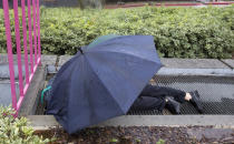 A man sleeps on top of a vent in rain at Grand Park in Los Angeles Thursday, Jan. 17, 2019. Rain and snow fell from one end of the state to the other, canceling flights, uprooting trees, knocking down power lines and causing localized flooding. (AP Photo/Damian Dovarganes)