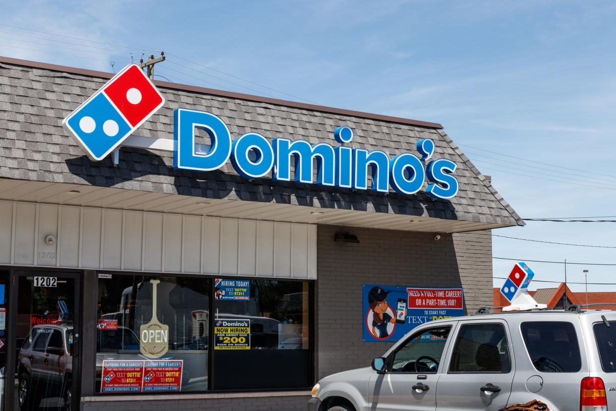 Domino's Pizza Restaurant exterior with rusty silver SUV parked by front door.