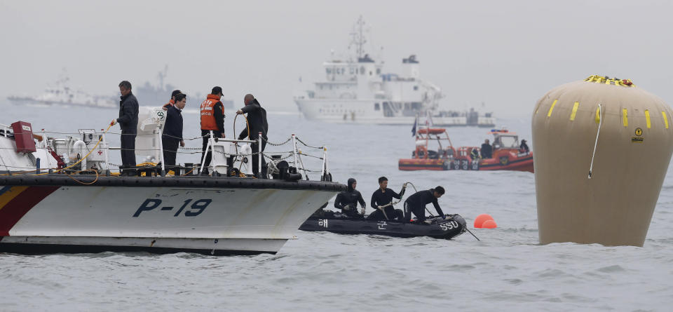 South Korean navy personnel install a buoy to mark the sunken passenger ship Sewol in the water off the southern coast near Jindo, South Korea, Friday, April 18, 2014. Rescuers scrambled to find hundreds of ferry passengers still missing Friday and feared dead, as fresh questions emerged about whether quicker action by the captain of the doomed ship could have saved lives. (AP Photo/Yonhap) KOREA OUT