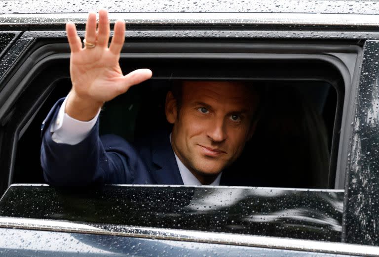 Emmanuel Macron saluda desde su auto tras votar en la segunda ronda legislativa