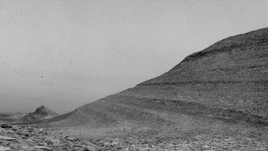  A grainy black-and-white image of a distant hill. 