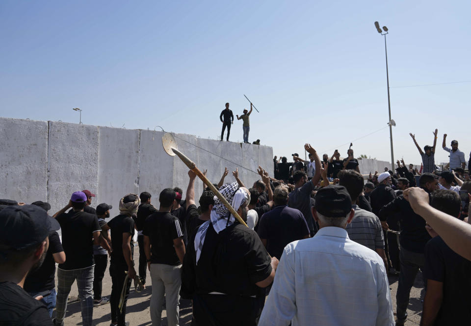 Supporters of Shiite cleric Muqtada al-Sadr try to remove concrete barriers in the Green Zone area of Baghdad, Iraq, Monday, Aug. 29, 2022. (AP Photo/Hadi Mizban)