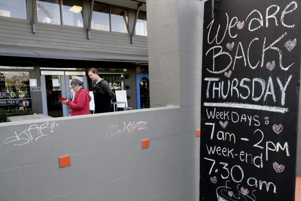 Customers enter their details before entering a cafe in Christchurch, New Zealand, Thursday, May 14, 2020. New Zealand lifted most of its remaining lockdown restrictions from midnight Wednesday as the country prepares for a new normal. Malls, retail stores and restaurants are all reopening Thursday in the South Pacific nation of 5 million, and many people are returning to their workplaces. (AP Photo/Mark Baker)