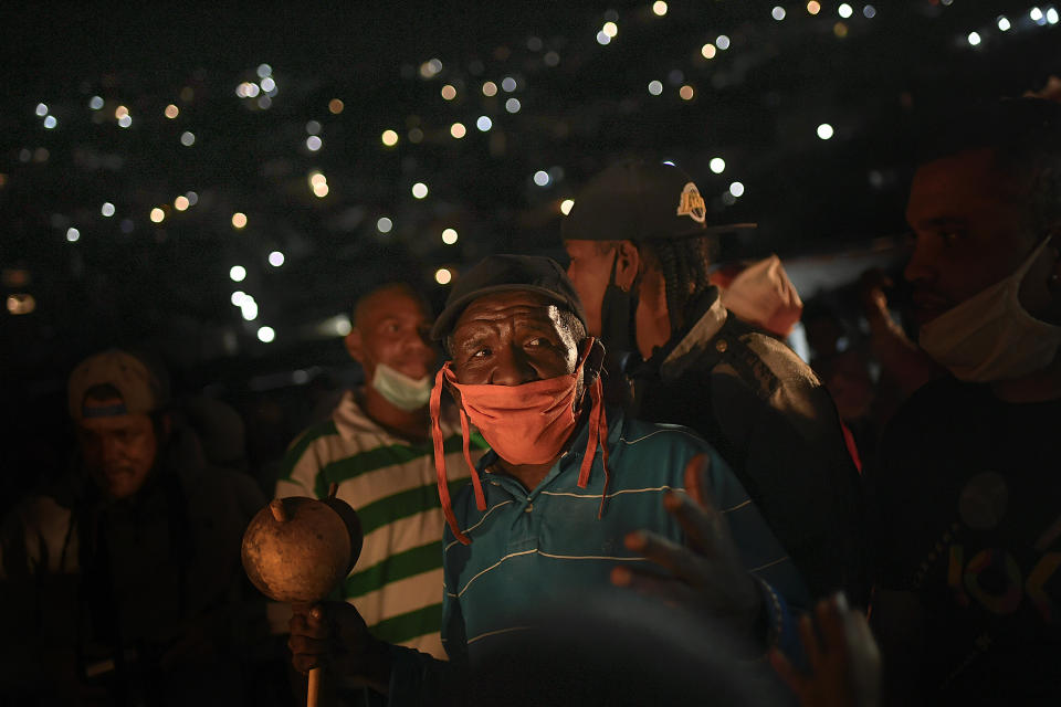 A man wearing a face mask amid the new coronavirus pandemic sings and prays during an overnight, Catholic religious procession in the San Agustin neighborhood of Caracas, Venezuela, early Monday, June 1, 2020. A small statue of Saint John the Baptist was carried from the home of a resident, who was its custodian for the year, to an outdoor altar, and was later carried to the home of another custodian where it will stay until next year's celebration. (AP Photo/Matias Delacroix)