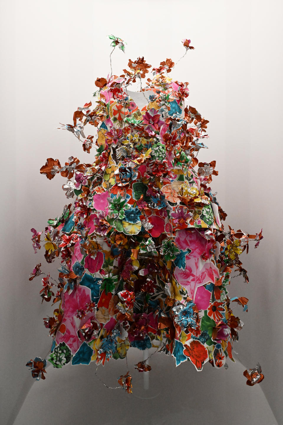 Sculpture of a human figure made from assorted floral fabric, creating a burst of flowers from the body