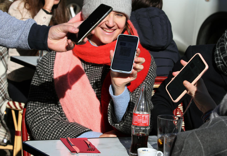 A waiter checks clients' vaccine passes at a restaurant in Saint Jean de Luz, southwestern France, Monday, Jan.24, 2022. Unvaccinated people are no longer allowed in France's restaurants, bars, tourist sites and sports venues, as a new law came into effect Monday requiring a "vaccine pass" that is central to the government's anti-virus strategy. (AP Photo/Bob Edme)