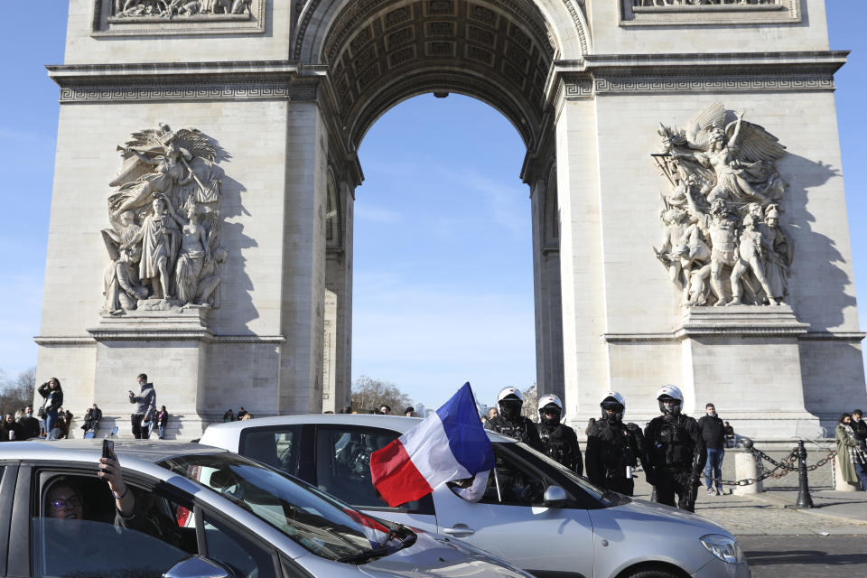 Protesters part of a convoy drives past the Arc de Triomphe on the Champs-Elysees avenue, Saturday, Feb.12, 2022 in Paris. Paris police intercepted at least 500 vehicles attempting to enter the French capital in defiance of a police order to take part in protests against virus restrictions inspired by the Canada's horn-honking "Freedom Convoy." (AP Photo/Adrienne Surprenant)