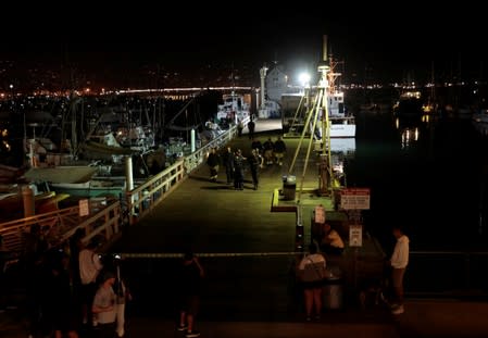 Rescue personnel exit the city pier after unloading the victims of a pre-dawn fire that sank a commercial diving boat off the coast of Santa Barbara, California