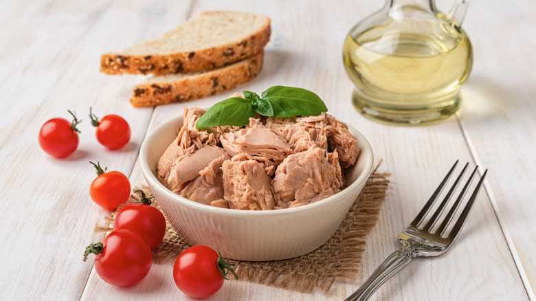 Tuna next to oil, bread, and tomatoes 