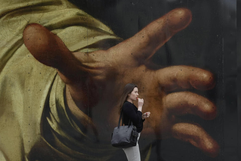 A woman walks past a poster featuring the painting of Caravaggio's "The Supper at Emmaus", outside the National Gallery, in London, Wednesday, Sept. 13, 2023. (AP Photo/Kin Cheung)