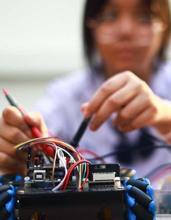 A close up of a person tinkering with electrical wires in a device. 