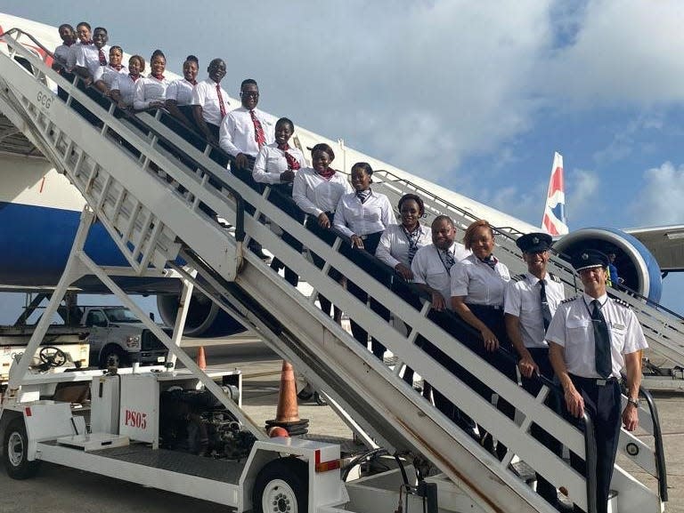 An all-black crew standing in a line on the portable airplane stairs