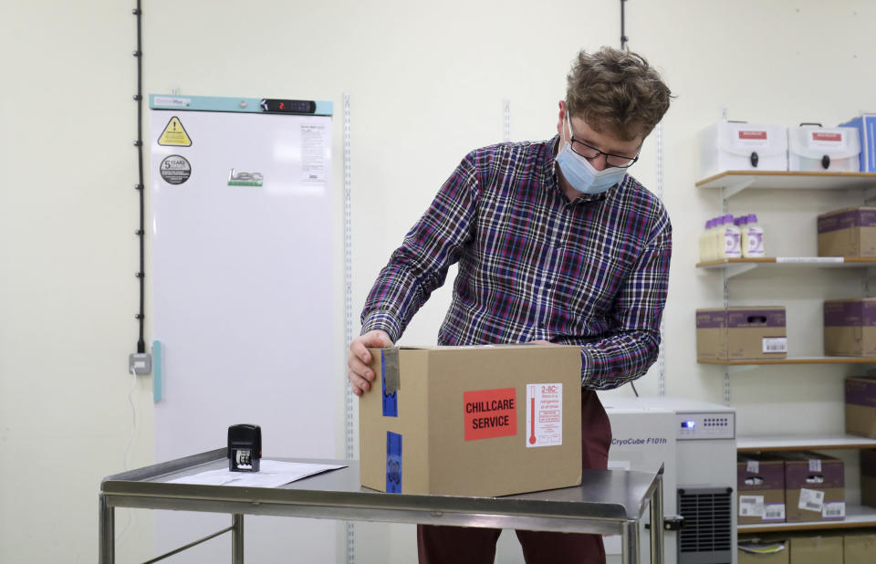 Assistant Technical Officer Lukasz Najdrowski unpacks doses of the COVID-19 vaccine developed by Oxford University and U.K.-based drugmaker AstraZeneca as they arrive at the Princess Royal Hospital in Haywards Heath, England, Saturday Jan. 2, 2021. The UK has 530,000 doses available for rollout from Monday. (Gareth Fuller/Pool via AP)