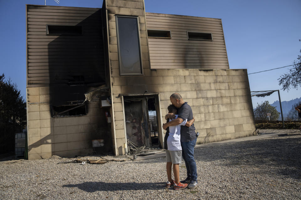 FILE - Alex Codonyer, 55, hugs his son Alan, 12, next to their house burnt during a wildfire in River Park village, near the town of El Pont de Vilomara, Spain, July 19, 2022. Major wildfires in Europe are starting earlier in the year, becoming more frequent, doing more damage and getting harder to stop. And, scientists say, they’re probably going to get worse as climate change intensifies unless countermeasures are taken. (AP Photo/Emilio Morenatti, File)