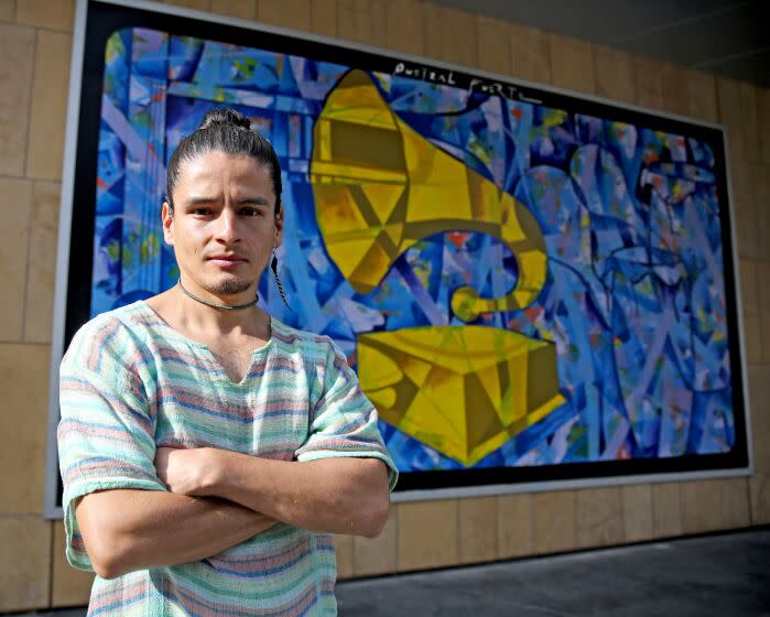 Quetzal Fuerte, 34 of Mexico, who was commissioned to paint a mural on the outside wall of the Grammy Museum, poses in front of the mural, in Los Angeles, on Friday, Nov. 11, 2022.