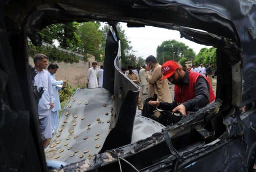 Pakistani rescuers inspect the badly damaged US consulate vehicle at a bomb blast site in Peshawar. A suicide car bomber rammed a US consulate vehicle in Pakistan on Monday, killing at least two people in the deadliest attack targeting Americans in the country in more than two years