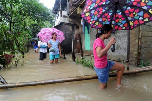 People wade through floodwaters in Quezon City Suburban Manila on August 6, 2012. Residents of low-lying slums fled the huge shantytowns lining Manila's rivers and sewers for the safety of schools, gymnasiums and government buildings, the civil defence office said