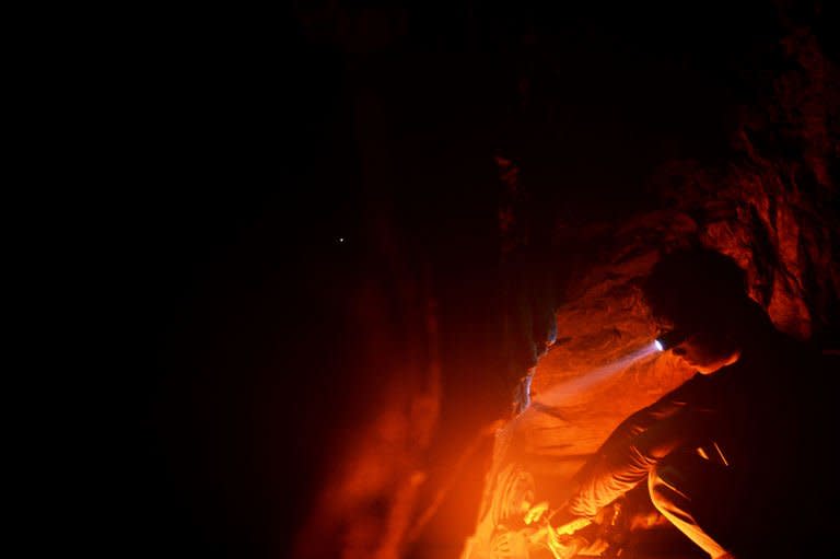 Indian coal miner, Surya Limu, keeps warm by a fire in a deep mine shaft in Rymbai village, Meghalaya on January 29, 2013. Limu, who claims he is 17, left his native Nepal for Meghalaya when his father died in a house fire, leaving behind a widow and two children