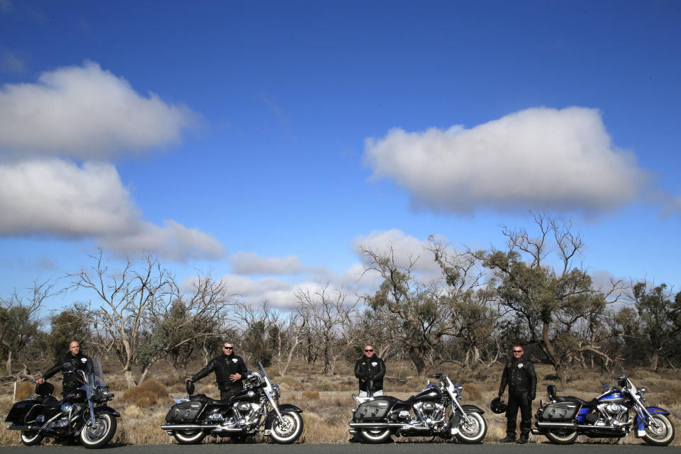 In this May 26, 2013 photo, motorcycle tourists from left, John Roe, Rob Griffith, Glenn Nicholls and Stefan Hersee pose next to their bike as they rest on the roadside near Wentworth, 1,043 kilometers (648 miles) from Sydney, Australia, during a seven-day, 3,000-kilometer (1,900-mile) journey across the Outback. (AP Photo/Rob Griffith)