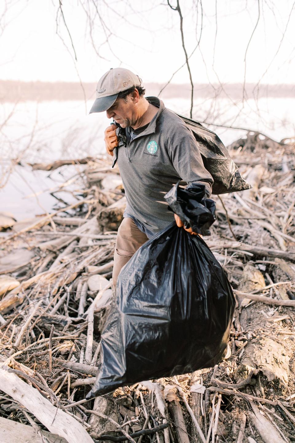 John Naylor removes bags of plastic items he cleaned up from the banks of the Susquehanna River near Wrightsville, Pa.