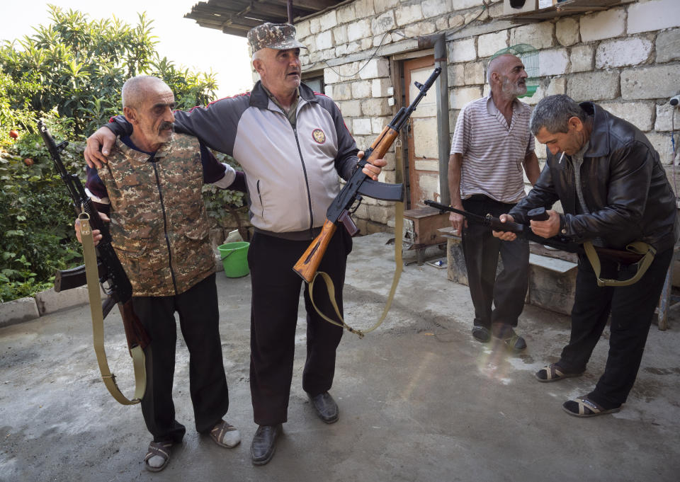 Local residents hold Kalashnikov guns that they received from a recruitment office in the town of Martuni, the separatist region of Nagorno-Karabakh, Wednesday, Oct. 14, 2020. The conflict between Armenia and Azerbaijan is escalating, with both sides exchanging accusations and claims of attacks over the separatist territory of Nagorno-Karabakh. Heavy fighting is in a third week despite a cease-fire deal. (AP Photo)