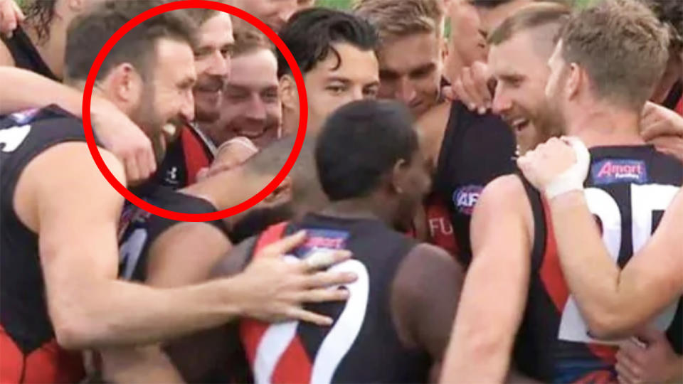 Essendon players are pictured laughing in their huddle before the second half of their match against Geelong.