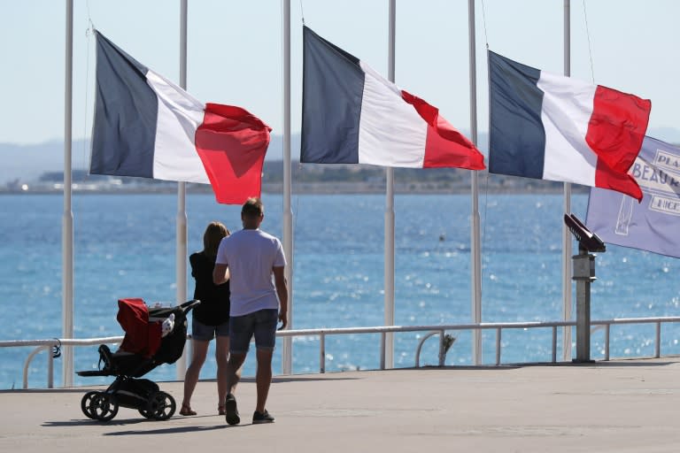 People walk past French flags lowered to half-mast in Nice, southern France, on July 16, 2016, following the deadly Bastille Day attack two days before