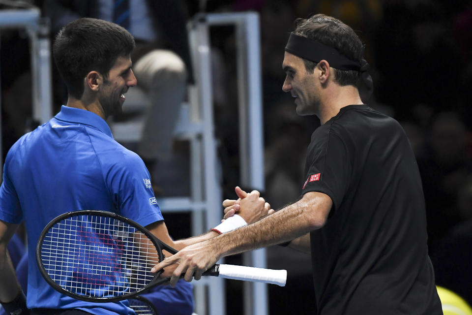 Roger Federer of Switzerland, right, and Novak Djokovic of Serbia shake hands after winning the match point during their ATP World Tour Finals singles tennis match at the O2 Arena in London, Thursday, Nov. 14, 2019. (AP Photo/Alberto Pezzali)