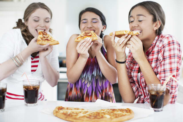 Teenage girls eating pizza