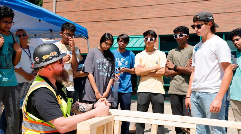 Students from Green Level High School watch as Bobbitt’s Paul Murray demonstrates how to toenail wood during Construction Field Day at Bobbitt Design Build in Raleigh, N.C., Tuesday, July 19, 2022. Around 100 Wake County high school students visited Bobbitt to see the kinds of high-paying jobs that are available in the construction industry. It’s part of the WakeEd Partnership’s Career Accelerator Program that’s giving 400 students a chance to learn more about jobs in different fields such as construction, the hospitality industry, health care and information technology.