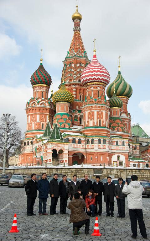 Chinese tourists pose for a photo in front of St Basil's church in the center of Moscow, on February 29, 2012