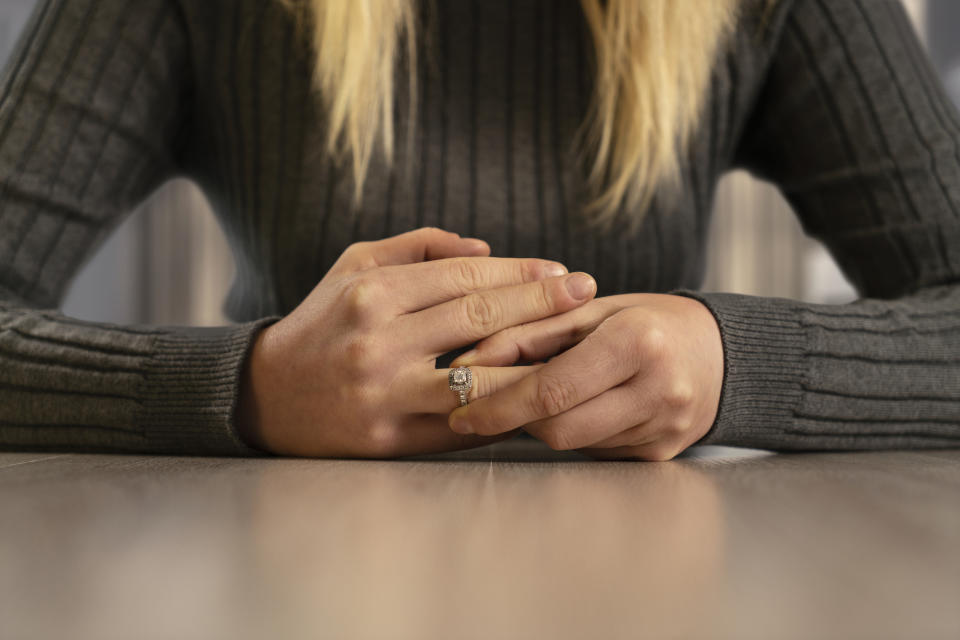 A woman sitting at a table and wearing a ring