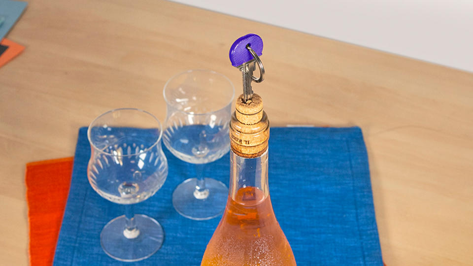 Using a key to remove a cork from a wine bottle