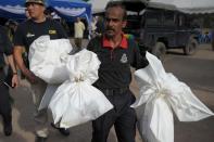 A Malaysian policeman carries human skeletal remains inside plastic bags exhumed from graves following the discovery of numerous grave sites and detention camps near the Malaysia-Thailand border