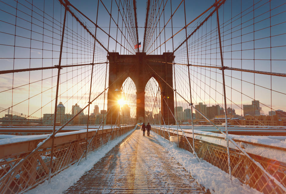 Couple crossing brooklyn Bridge at sunsire, New York