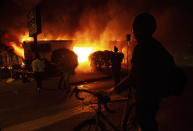 A protester looks on at a burning building in Minneapolis, early Saturday, May 30, 2020, amid protests against the death of George Floyd in police custody on Memorial Day. (Khadejeh Nikouyeh/News & Record via AP)