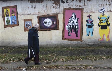 A woman walks past a wall with graffiti in Valka October 26, 2013. REUTERS/Ints Kalnins