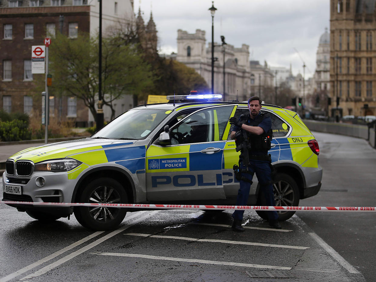 An armed police officer stands guard inside a police cordon outside the Houses of Parliament after the terrorist incident: Getty