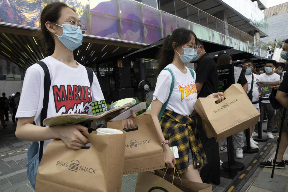 Customers leave with their purchase at the opening of the first Beijing outlet for Shake Shack in Beijing on Wednesday, Aug. 12, 2020. The U.S. headquartered burger chain is opening its first Beijing restaurant at a time when China and the U.S. are at loggerheads over a long list of issues. (AP Photo/Ng Han Guan)