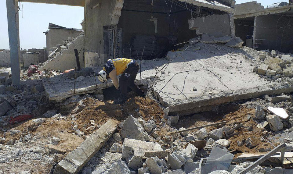 FILE - In this May 7, 2019 file photo provided by the Syrian Civil Defense group known as the White Helmets, shows a member of the White Helmets, searching for victims under the rubble of a house that was destroyed by a Syrian government forces airstrike, in the village of Ras el-Ain, in the northwestern province of Idlib, Syria. Russia said Sunday, May 19, 2019, that Syrian government forces have unilaterally ceased fire in the northern Idlib province, the last major rebel stronghold. Fighting erupted in Idlib last month, effectively shattering a cease-fire negotiated by Russia and Turkey that had been in place since September. (Syrian Civil Defense White Helmets via AP, File)