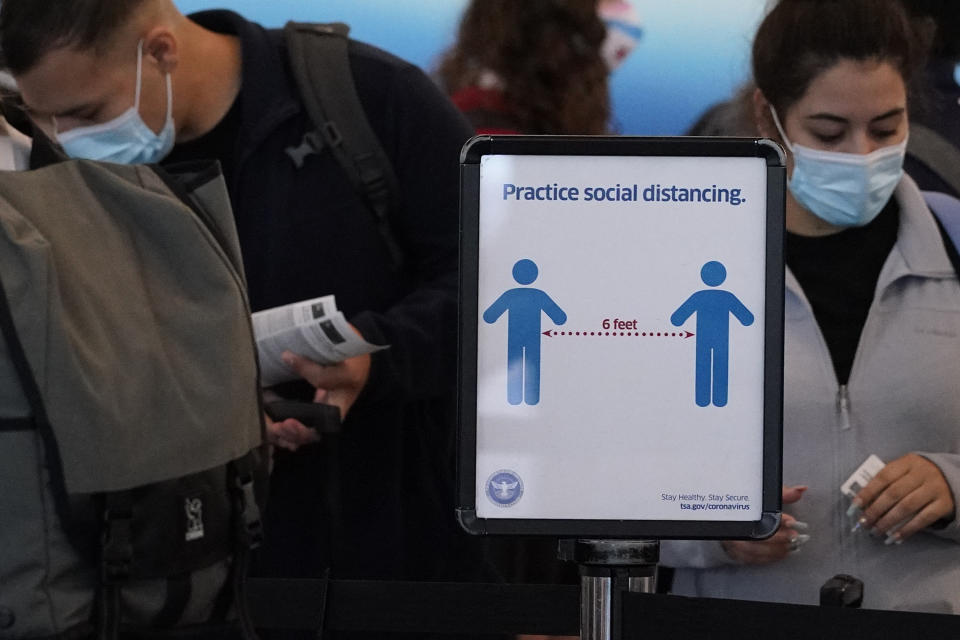 Travelers wait to check-in for their flights as a sign reminding travelers to social distance is displayed in Terminal 3 at O'Hare International Airport in Chicago, Friday, July 2, 2021. (AP Photo/Nam Y. Huh)