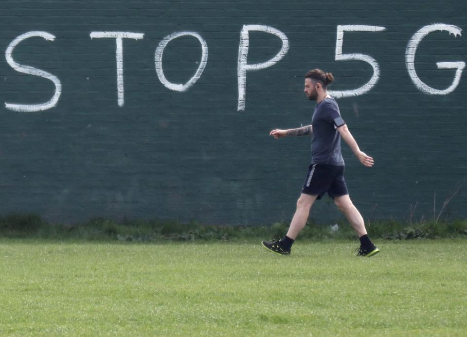 A man exercising during coronavirus lockdown walks past a graffiti that reads 'STOP 5G' in London, 8 April, 2020Reuters