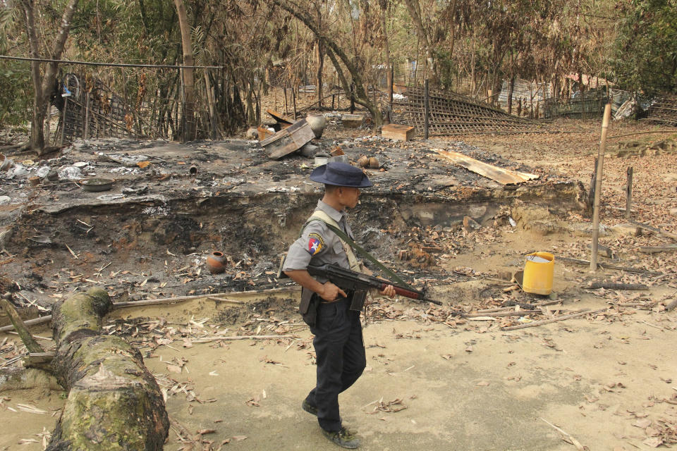 FILE - In this Sept. 6, 2017, file photo, a Myanmar security officer walks past burned Rohingya houses in Ka Nyin Tan village of suburb Maungdaw, northern Rakhine state of western Myanmar. Myanmar’s government announced Wednesday, Nov. 20, 2019 that its leader, Aung San Suu Kyi, will head a legal team it will send to the International Court of Justice in the Netherlands to contest a case of genocide filed against it by Gambia on behalf of the Organization of Islamic Cooperation. (AP Photo, File)