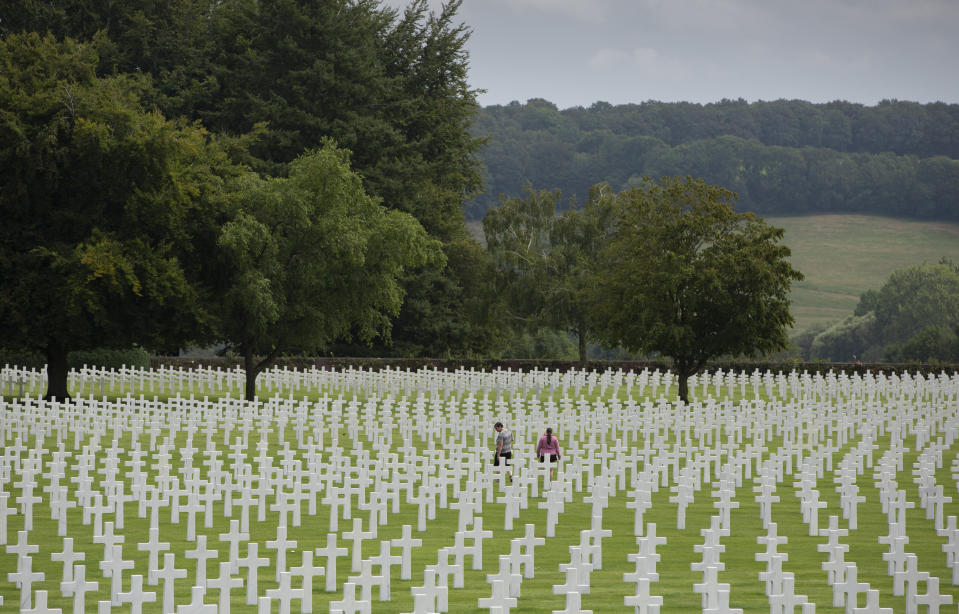 In this Aug. 8, 2019 file photo, visitors walk among the headstones at the Henri Chapelle World War II cemetery in Henri Chapelle, Belgium. The cemetery contains 7,992 American war dead and covers 57 acres. Due to coronavirus concerns American war cemeteries are currently closed in Belgium. (AP Photo/Virginia Mayo, File)