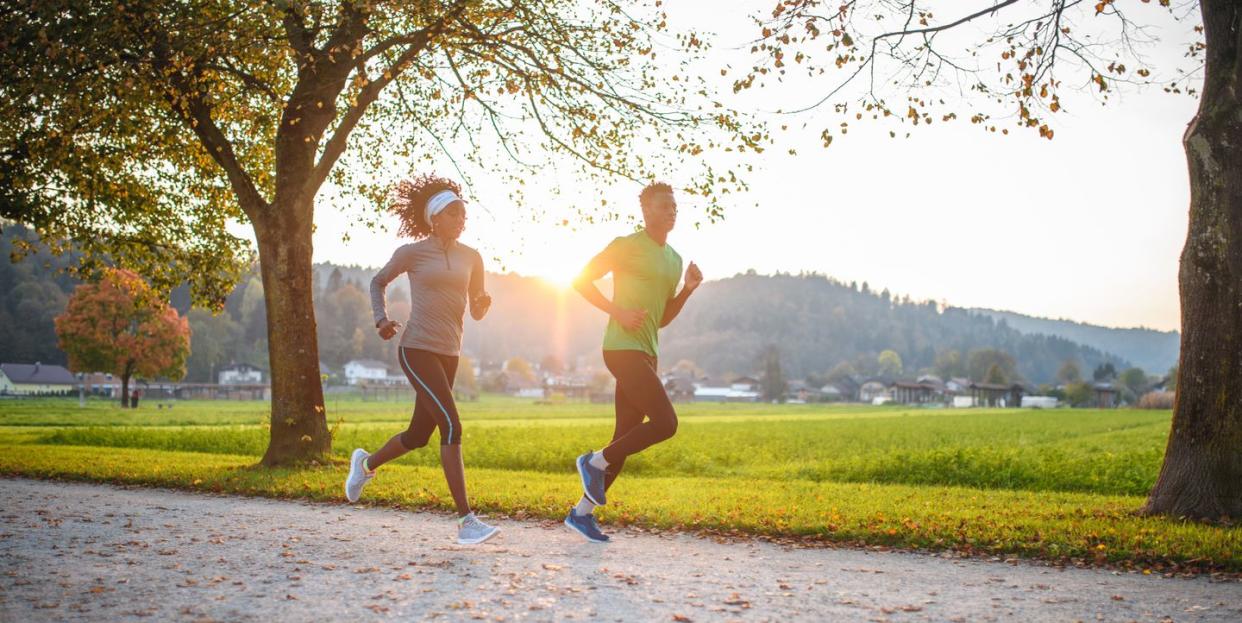 dedicated athletes running in public park at sunset