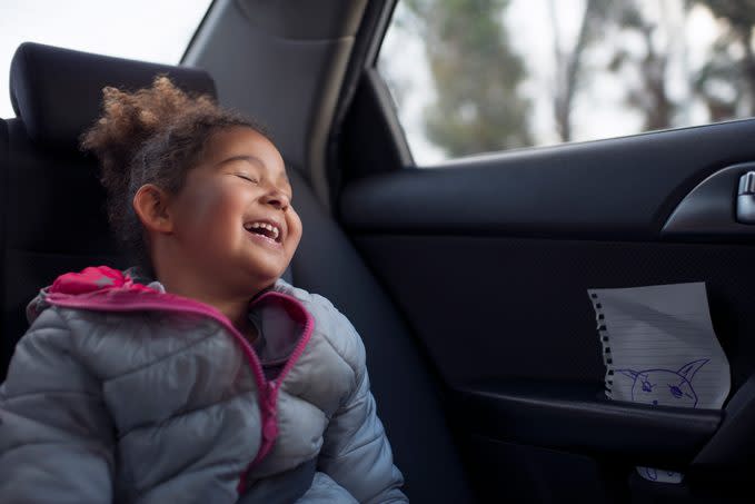 Happy excited passenger child girl traveling on the rear vehicle seat.